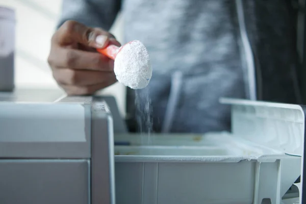 Ρίχνει σκόνη πλυσίματος σε πλαστικό δίσκο του πλυντηρίου ρούχων — Φωτογραφία Αρχείου