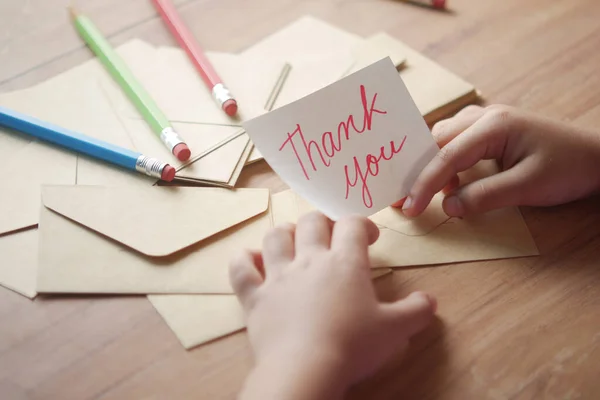 Niño mano sosteniendo gracias carta en la mesa —  Fotos de Stock
