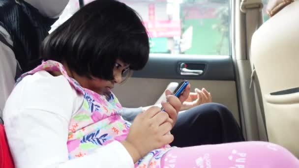 Дитяча дівчина дивиться мультфільм на смартфон в машині — стокове відео