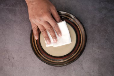 Genç adamın bir bez parçasıyla tabağı silmesine yakın durun. 