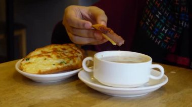 hand pick a garlic bread and soup on table 