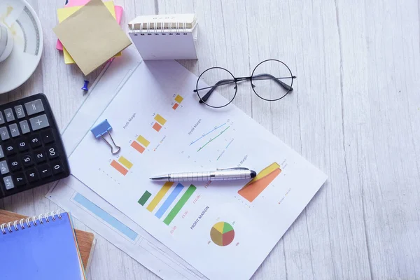 finansal grafik, hesap makinesi ve not defteri masanın üzerinde 