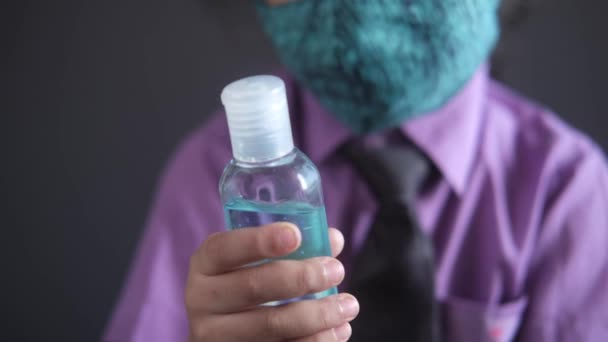 Child in school dress in face mask holding hand sanitizer — Video