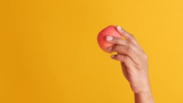 Person hand hålla äpple på gul bakgrund — Stockvideo