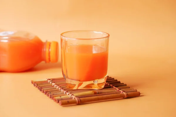 Vaso de zumo de naranja y botella sobre fondo de color — Foto de Stock