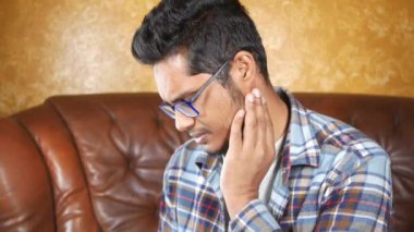 Genç adam acı veren kulağına dokunuyor. ,