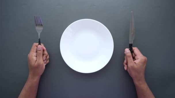Muži drží příbory s prázdným talířem na černém pozadí — Stock video