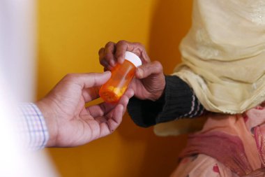 Doktor, yaşlı hastasına ilaç kutusu veriyor. 