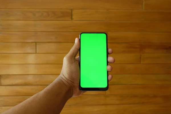 Крупним планом молода людина рука використовує смартфон з зеленим екраном — стокове фото