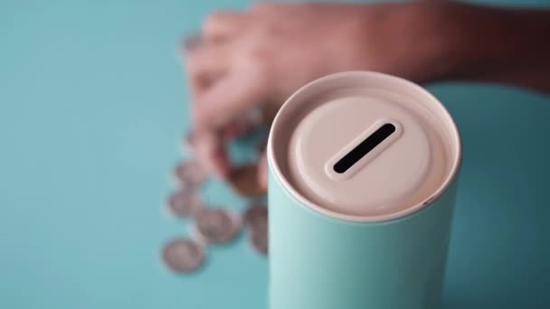 Unge spara mynt i en burk på färg bakgrund — Stockvideo