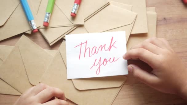 Mão criança segurando carta de agradecimento na mesa — Vídeo de Stock