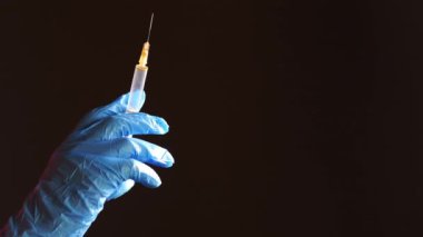 Doktor elinde şırınga tutan tıbbi eldivenler getirdi..
