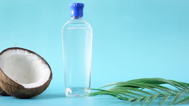 Plak verse kokosnoot en een fles olie op een blauwe ondergrond — Stockvideo