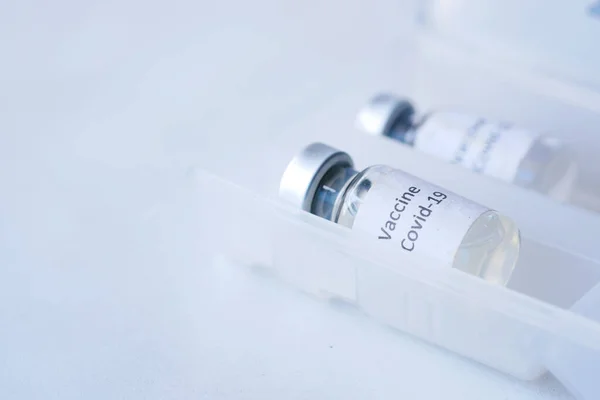 Fechar a vacina contra o coronavírus numa caixa de fundo branco — Fotografia de Stock