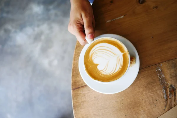 Vista superior de uma xícara de café tardio com design de forma de coração no topo na mesa de café — Fotografia de Stock
