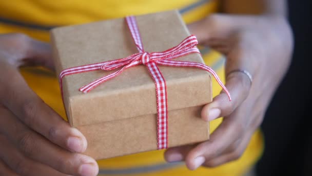 Ребенок рука держит самодельный подарочный коробок на желтом фоне — стоковое видео