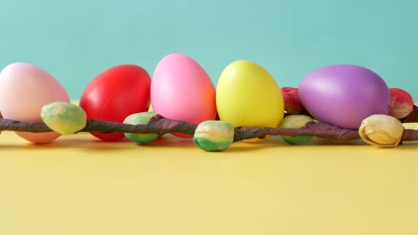 Concepto de Pascua con huevos multicolores y flor en la mesa — Vídeo de stock