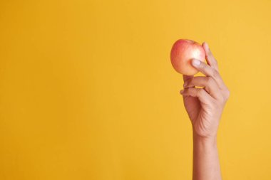  Çocuk elleri sarı arka planda bir elma tutuyor. 