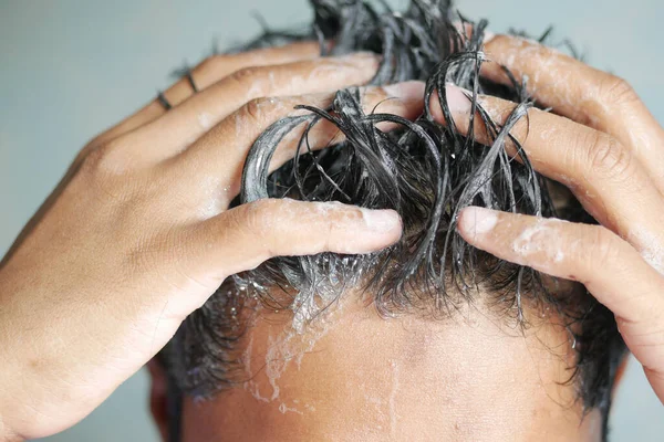 Homens jovens lava h seu cabelo com xampu . — Fotografia de Stock