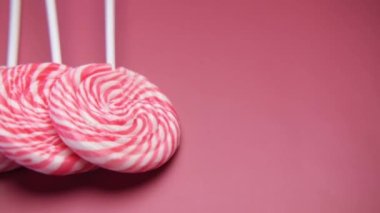 Kırmızı arkaplanda gökkuşağı kalp şeklindeki lolipopu kapat 