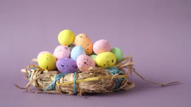 Mor zemin üzerinde çok renkli yumurta bulunan paskalya konsepti.