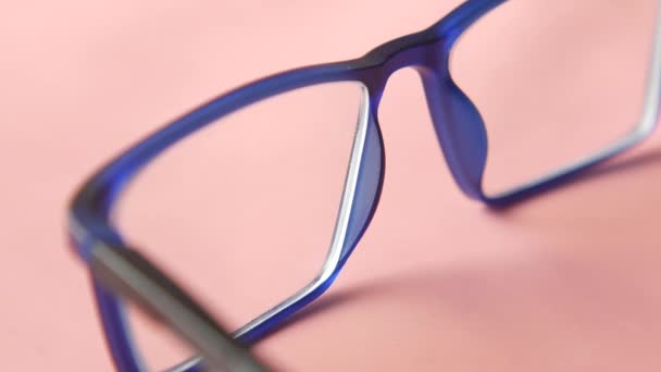 Close-up van blauwe kleur bril op roze — Stockvideo