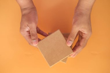 Turuncu arka planda ev yapımı hediye kutusu var. 