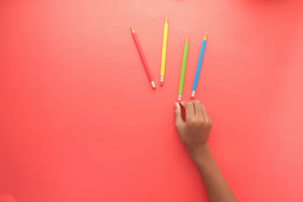 Niño mano recoger lápices de color sobre fondo rojo —  Fotos de Stock