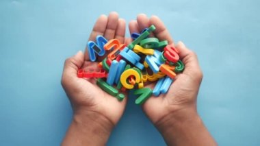 Çocuk elinin üzerinde renkli plastik harfler 