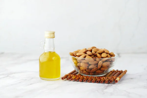 Minyak almond dalam botol dan mur dalam mangkuk di atas meja dengan ruang fotokopi — Stok Foto