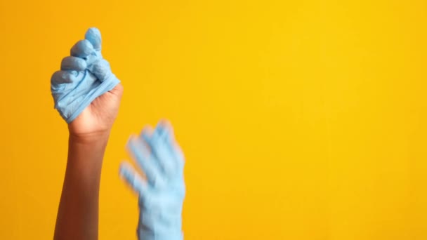 Чоловік лікар носить медичні рукавички на жовтому фоні — стокове відео