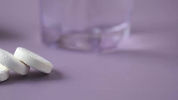 Comprimidos solúveis efervescentes e vidro de água sobre fundo roxo — Vídeo de Stock