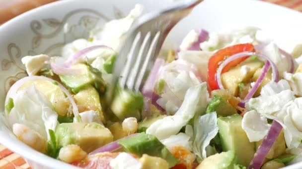 Het eten van avocado salade in kom op tafel — Stockvideo