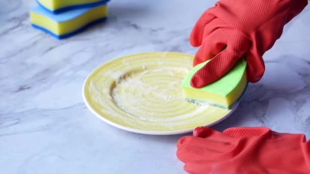 Губка, резиновые перчатки и разноцветная тарелка на голубом — стоковое видео