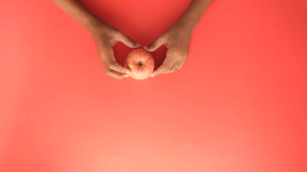 Barn pojke hand hålla ett äpple på röd bakgrund — Stockvideo