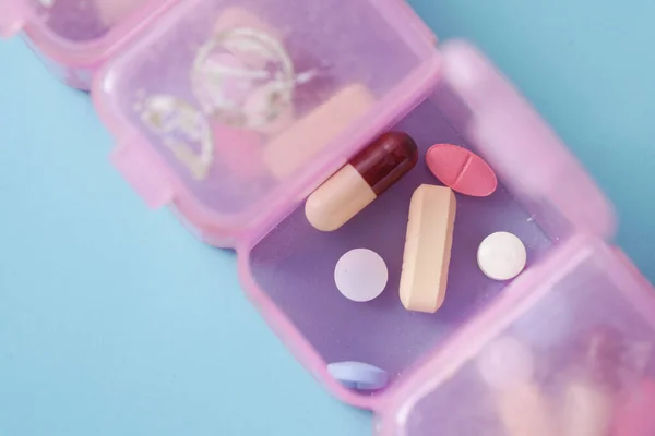 Вид зверху медичних таблеток у коробці для таблеток на кольоровому тлі — стокове фото