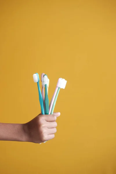Holding many colorful tooth brush against yellow — Stock Photo, Image