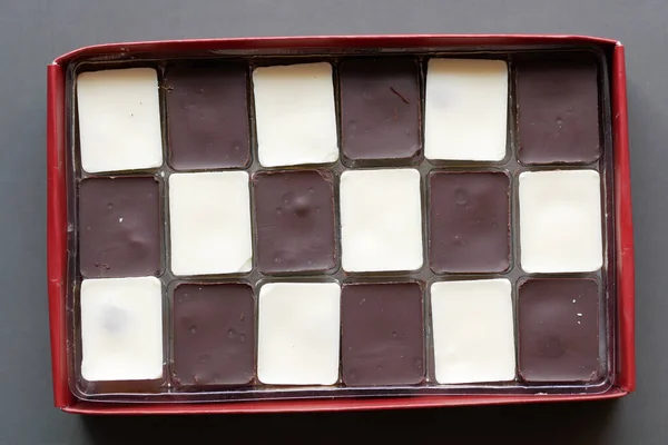 Dark and white chocolate in a box on gray background — Stock Photo, Image