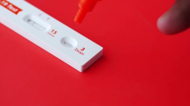 Kırmızı arkaplanda Covid-19 test kiti kullanılıyor 
