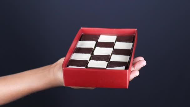 Bambino ragazzo in possesso di una scatola di cioccolato sul buio — Video Stock