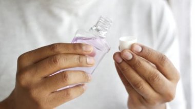  Mavi arka planda bir ağız gargarası sıvı kabını elle tut 
