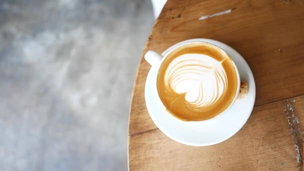 Вид сверху чашки позднего кофе с рисунком формы сердца на столике кафе — стоковое видео