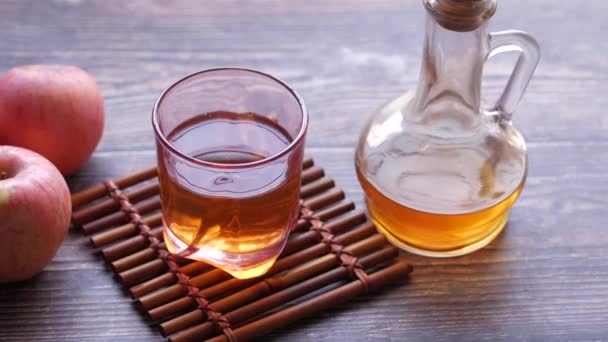 Vinagre de manzana en botella de vidrio con manzana verde fresca en la mesa — Vídeos de Stock