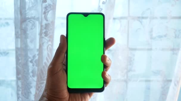 Primer plano de la mano del hombre joven utilizando el teléfono inteligente con pantalla verde — Vídeo de stock