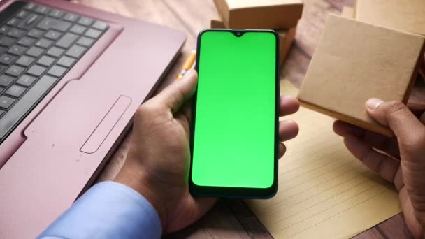 Porta smartphone con schermo verde e cartone sul tavolo — Video Stock