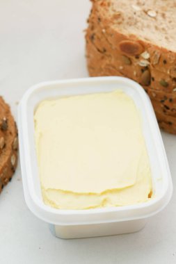 Beyaz zemin üzerinde ekmek olan bir kabın içinde taze tereyağı 