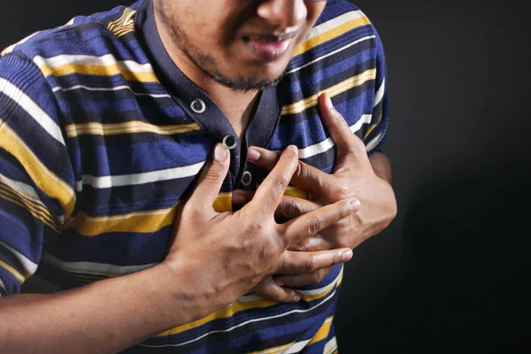 Jonge man lijden pijn in het hart en houden borst met de hand — Stockfoto