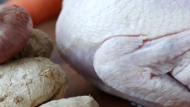 Сырая целая курица и овощи на столе — стоковое видео