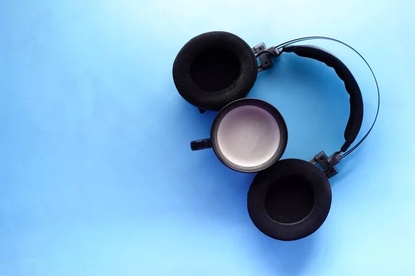 Kaffee und drahtlose Kopfhörer auf blauem Hintergrund — Stockfoto