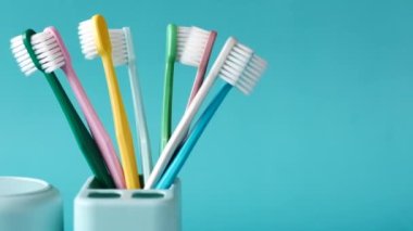  Açık yeşil arka planda beyaz kupada renkli diş fırçaları 